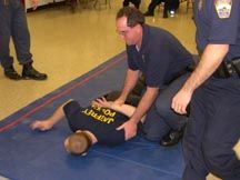 Sgt. Oswalt brings Off. Fetzner into a take-down maneuver. 